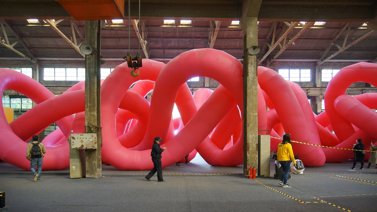 A vast pink knot in what looks to be an open public space with tall columns