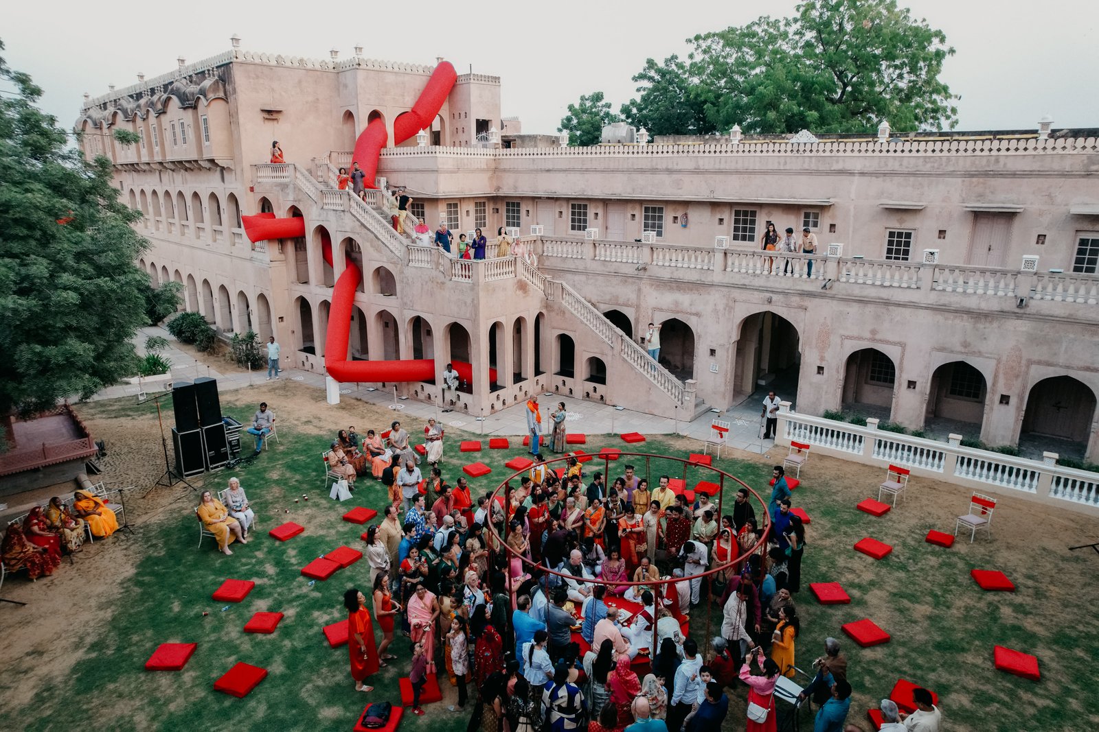 People in the courtyard of an Indian castle with a large inflatable artwork woven through recesses and windows