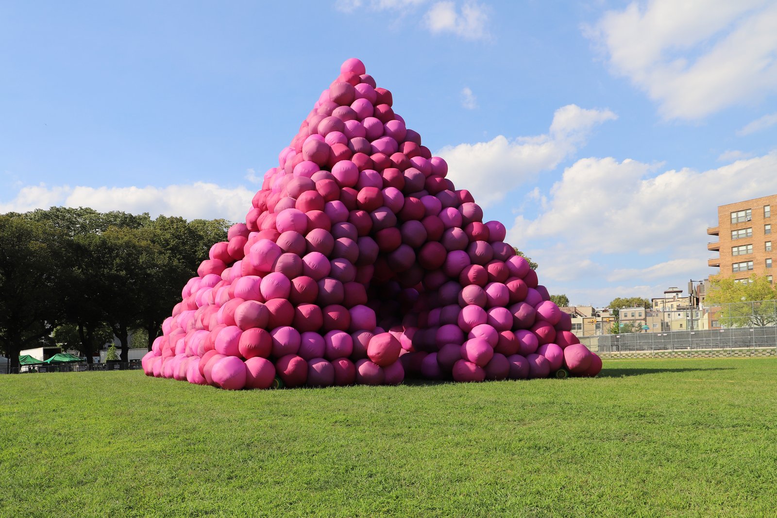 A large pyramid structure made from what appear to be purple balloons standing in a grassy field