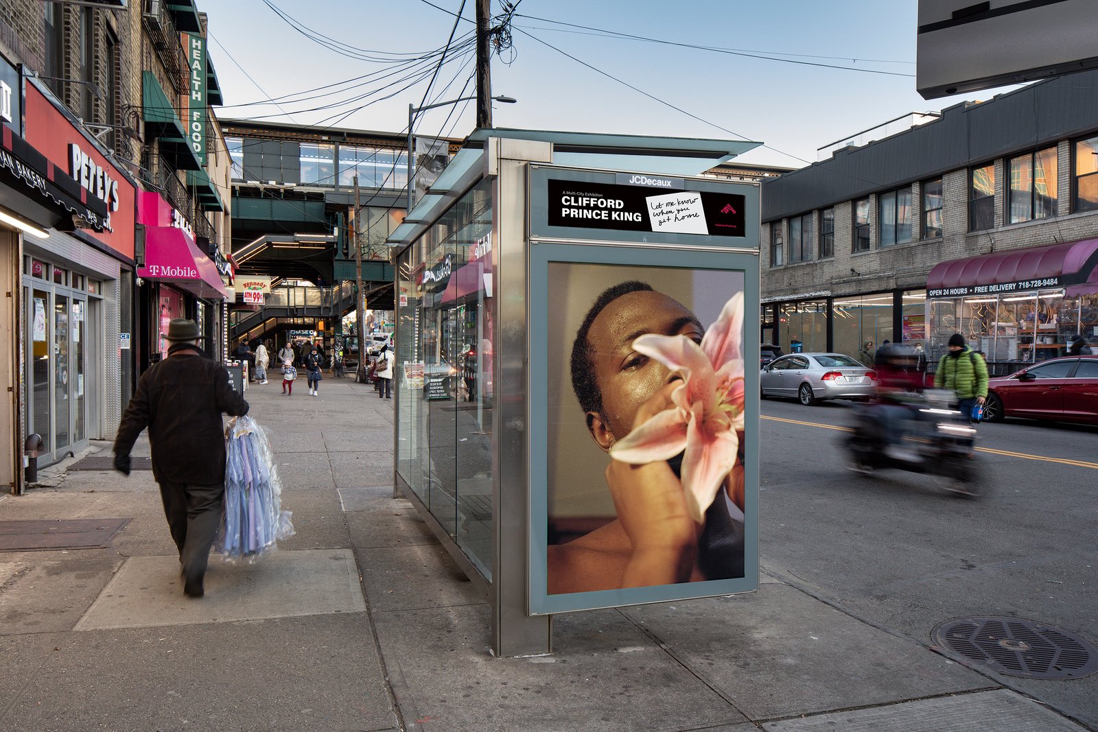 A street shot of a bus shelter featuring a man holding a flower in front of his face.