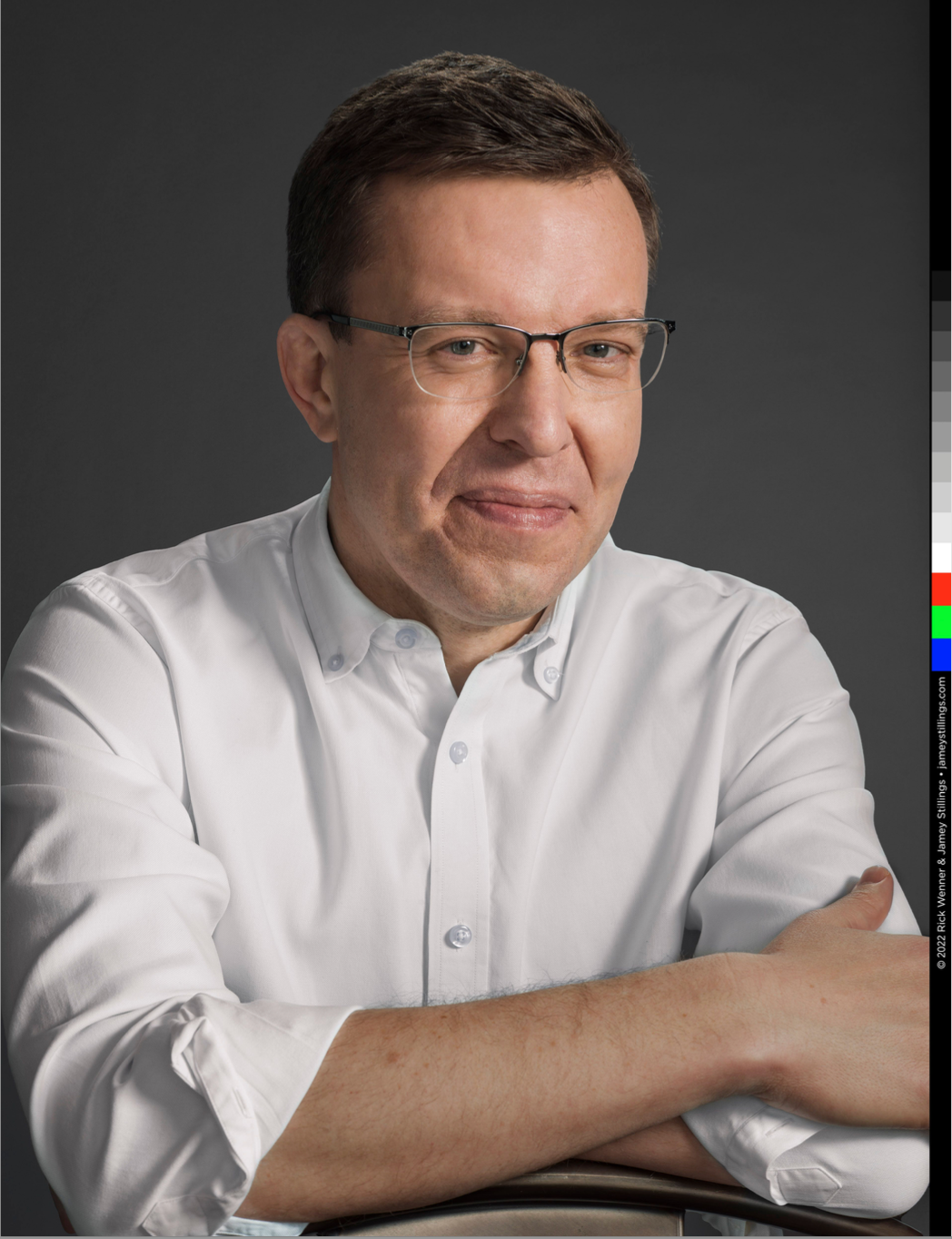 Man in white shirt and glasses poses with arms crossed