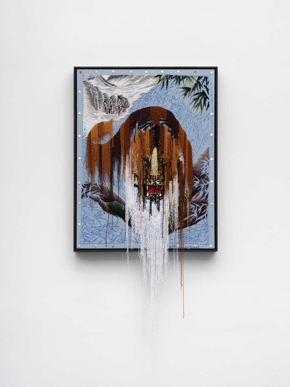 A mixed-media artwork hanging on a white gallery wal